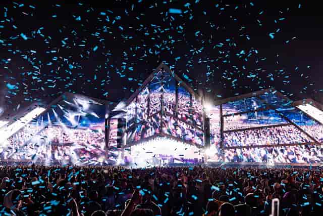Outdoor concert hall with vibrant lights, featuring a dynamic festival atmosphere.