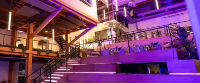 Modern multi-level event space with wooden finishes and vibrant lighting, perfect for gatherings.