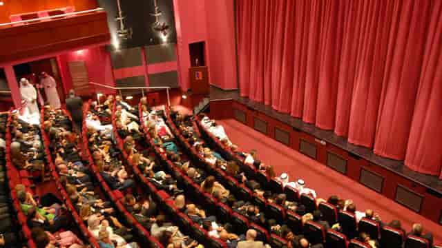 Main Auditorium at Courtyard Playhouse, vibrant red curtains, successful event seating.