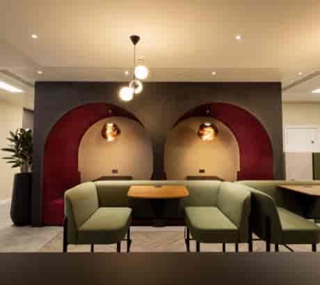 Modern office meeting space in Gilbanks, Manchester with green seating and warm lighting.
