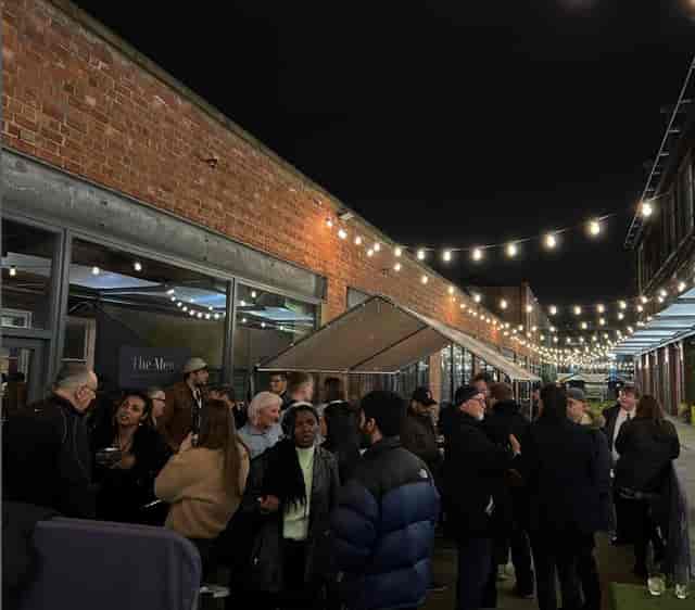 Outdoor terrace event with string lights for networking and socializing.