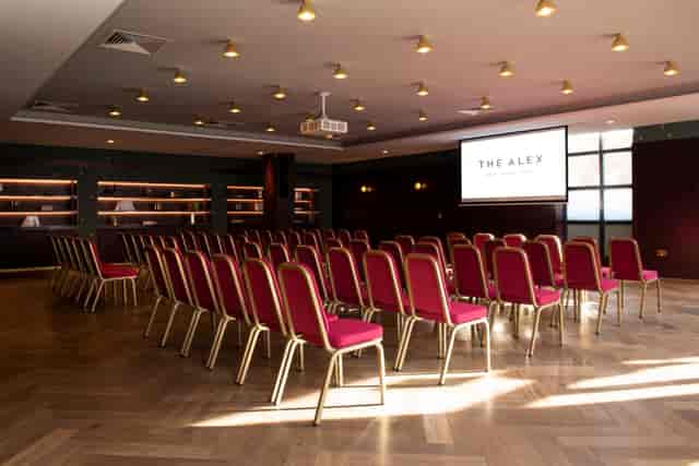 Red-upholstered chairs in sophisticated meeting space at The Odyssey, The Alex Hotel.