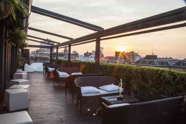 Milan rooftop lounge, cocktail reception, sunset skyline.