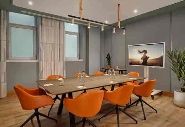 Modern meeting room at Citadines Holborn, featuring vibrant orange chairs for collaboration.