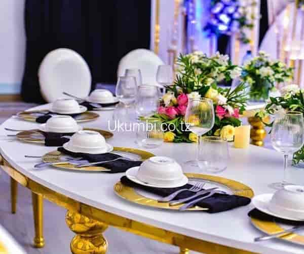 Elegant Ukumbi gala table setting, gold chargers, formal dinner.