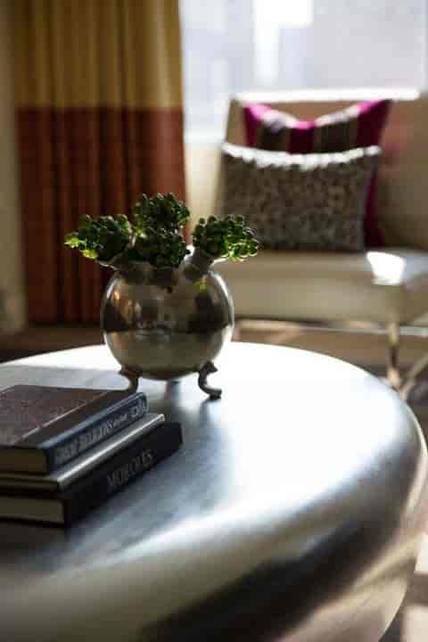Vegas event lounge, sophisticated centerpiece, metallic vase, greenery, books.
