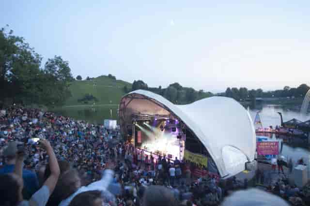 Outdoor concert, tent stage, Munich, amphitheater seating, waterfront.
