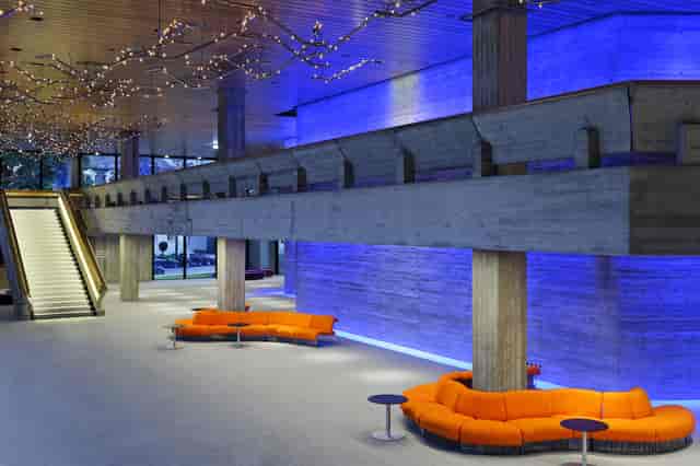 Brutalist Room Singold venue with orange seating for modern corporate networking reception.