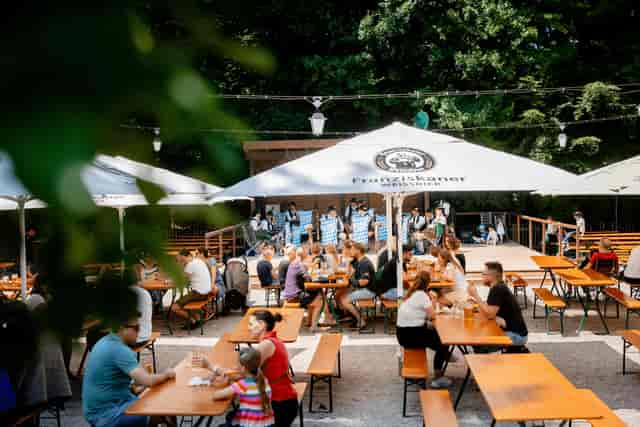 Networking event at Ayinger in der Au with communal bench seating and stage for outdoor parties.