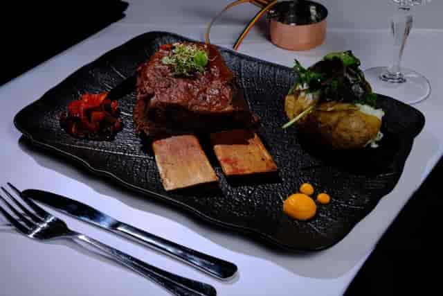 High-end plated entrée on black slate for premium gala dinners and VIP board meetings.