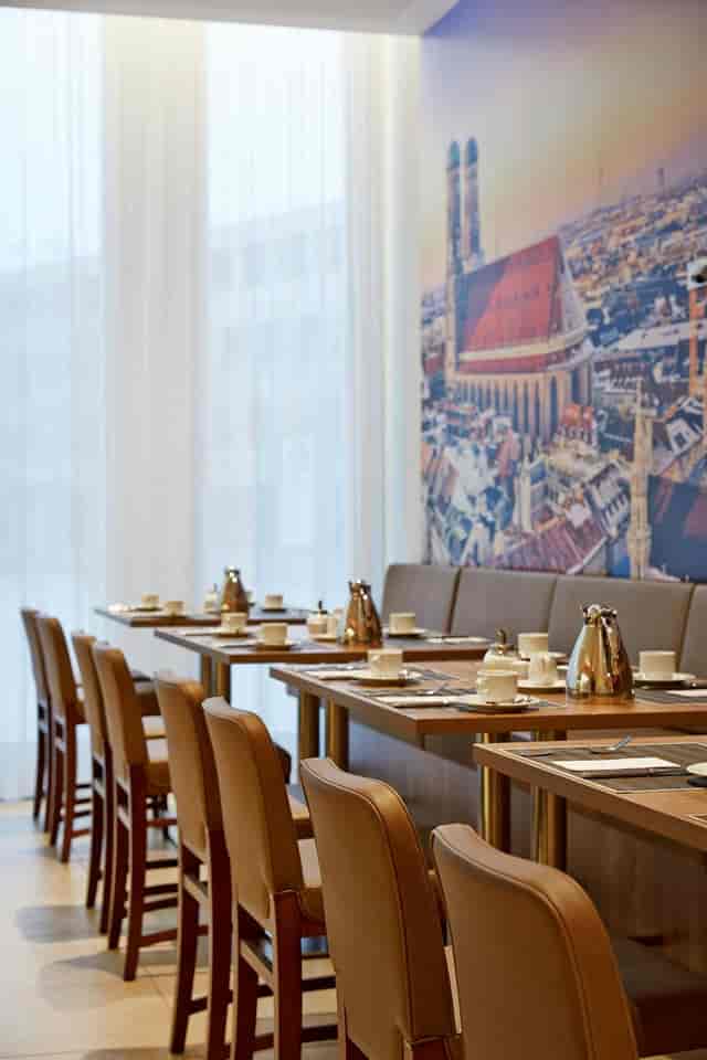 Leopold H4 Hotel München Messe banquet hall, clean table settings for corporate event space.