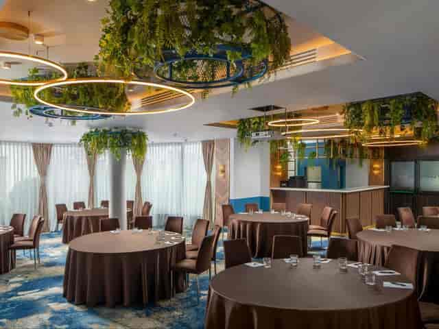 Modern event hall with elegant tables and greenery, ideal for meetings and receptions.