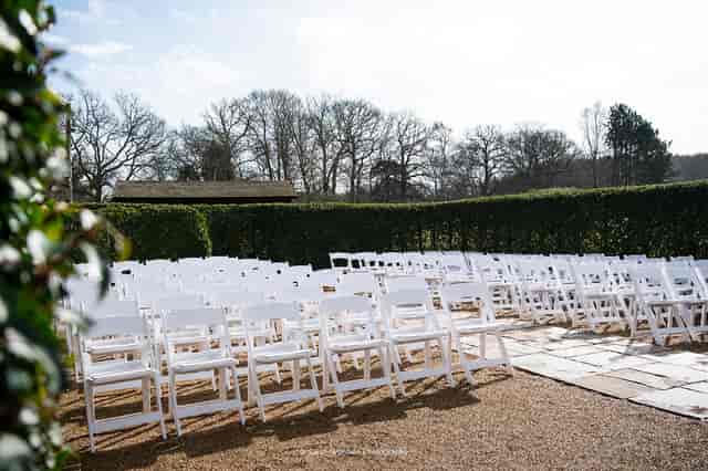 Outdoor garden wedding ceremony with white chairs and lush greenery at Brookfield Barn.