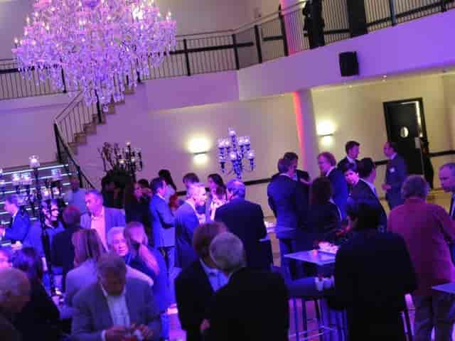 Networking reception at De Koning with purple lighting and candelabra centerpieces.