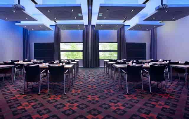 Modern conference room at The Manor Amsterdam with classroom seating and bold carpet for events.