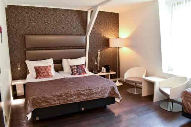 Modern double hotel room with seating area, ideal for business travel or corporate event lodging.