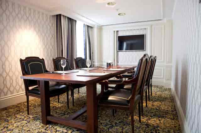 Business meeting room in Hotel Amsterdam Amstel with elegant wooden table and screen.