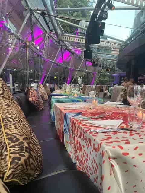 Immersive event dinner in clear-span structure with purple LED lighting.