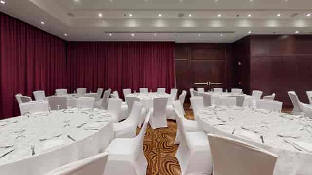 Najd Ballroom at Riyadh Marriott with burgundy drapes for luxury gala or corporate dinner events.