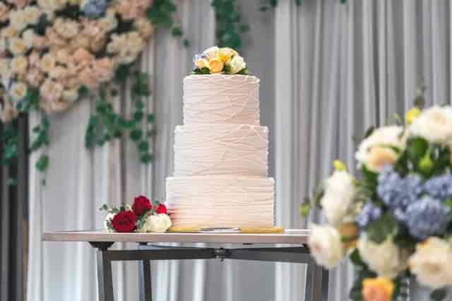 Elegant wedding cake display with floral arrangements at Village Square event center.
