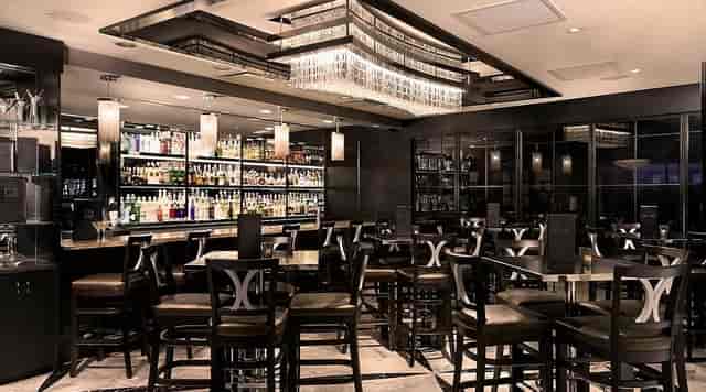 Upscale Morton's steakhouse bar with sleek high-top seating for corporate happy hour networking.