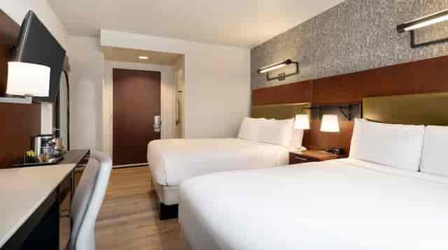 Double-queen hotel guest room with workspace for corporate event attendee lodging.