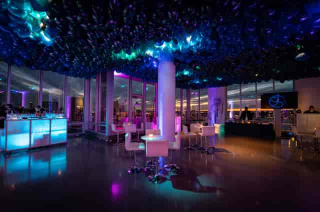 VIP event lounge with illuminated bars and balloon ceiling for corporate gala or brand launch.