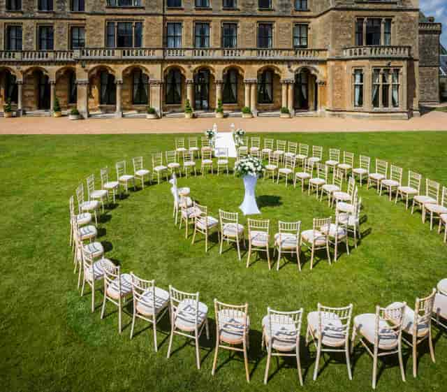 Outdoor wedding ceremony setup at Mercure Warwickshire Walton Hall Hotel with floral pedestal.