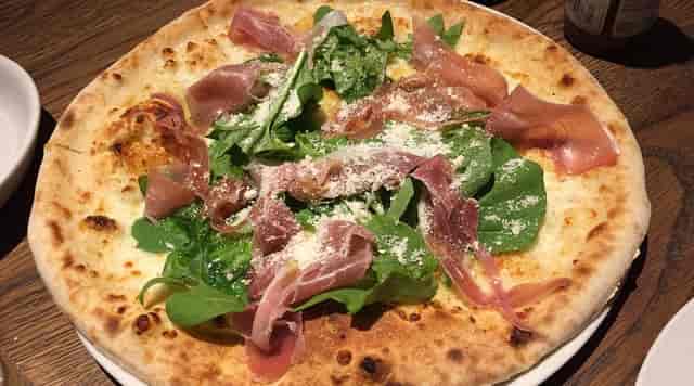 Artisanal prosciutto arugula pizza for casual networking lunch or corporate event catering.