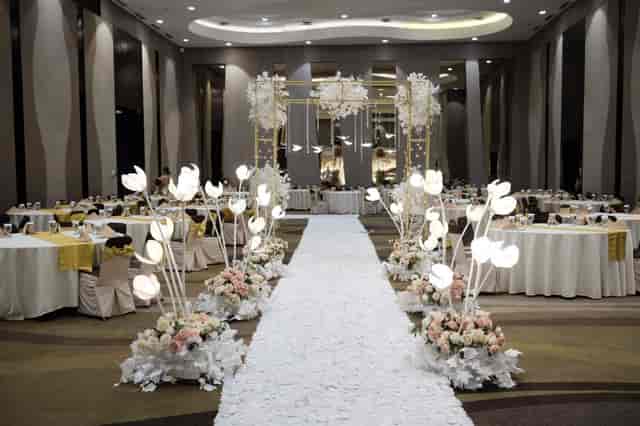Ballroom wedding gala with dramatic floral lighting and aisle runner at Hotel Santika.