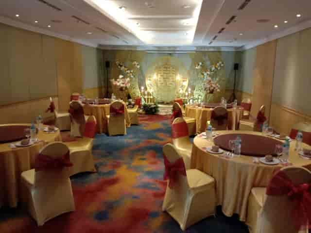 Gala banquet room with gold tables and decorated stage for wedding or corporate event.