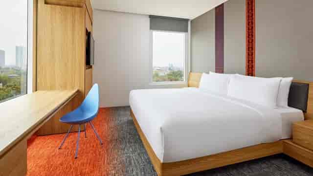 Modern Aloft South Jakarta guest room with functional workspace for business travel events.