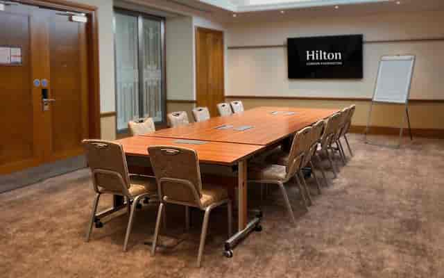 Meeting room at Hilton London Paddington with wooden table, ideal for corporate events.