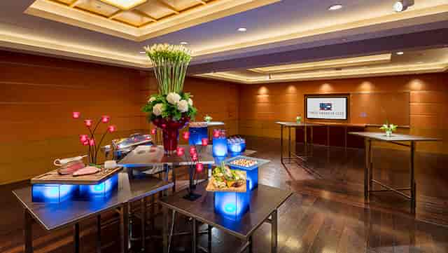 Illuminated catering station with floral centerpieces in Brooklyn Suite for networking reception.