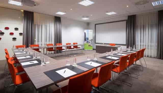 U-shaped meeting room in Lindner Hotel Frankfurt with orange chairs for workshops and conferences.