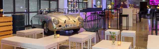 Vintage car centerpiece in industrial-chic loft gallery for unique event venue.