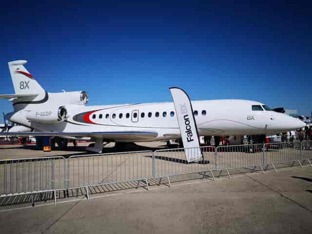 Aviation trade show at Paris Le Bourget with tarmac aircraft display and branded signage.