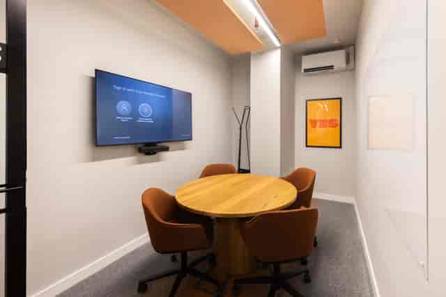 Huddle room with round table and whiteboard for collaborative meetings and brainstorming sessions.