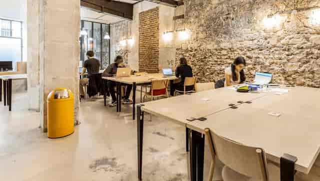 Industrial-chic co-working space with exposed brick, ideal for meetings and collaborative workspaces.