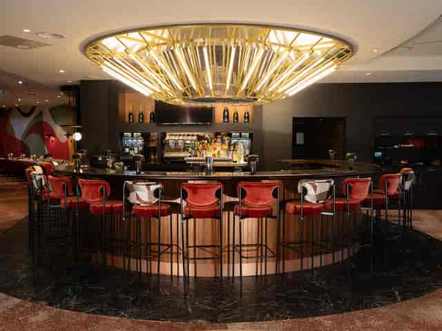 Curved cocktail bar with red velvet seating for sophisticated networking and corporate receptions.