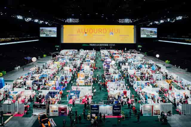 Trade show at Paris La Défense Arena with grid shell scheme and large digital branding.