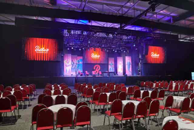 Studio 36 plenary setup with modular stage and cabaret seating for corporate events and conferences.