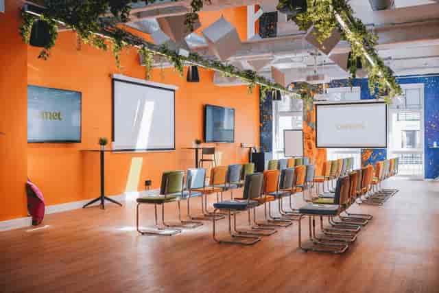 Theater-style meeting room at Comet Arboretum with vibrant orange walls for corporate events.