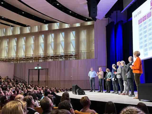 Erling Persson Hall: Tiered auditorium with panel stage for corporate conference and event setup.