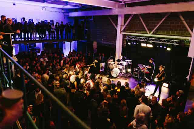 Multi-level industrial concert venue with stage lighting for live music events and performances.