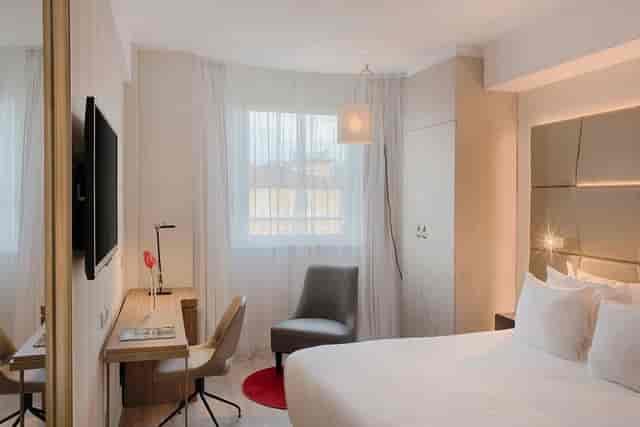 Modern NH Collection Roma Centro hotel room with ergonomic workspace for business conferences.