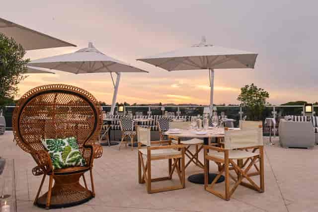 Rooftop sunset reception at Hotel Villa Pamphili Roma with bistro seating for networking events.