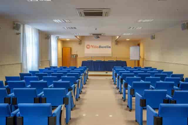 Theater-style Anfiteatro Room in Villa Aurelia with blue seating for corporate meetings or events.