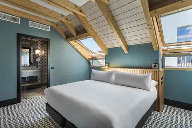 Alba Room Mate boutique suite with exposed wooden beams, ideal for VIP event room blocks.