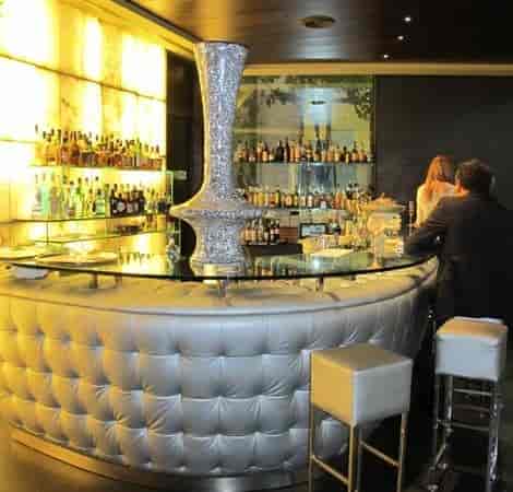 VIP reception at Glass Bar, Hotel Urban featuring backlit shelving and premium tufted seating.